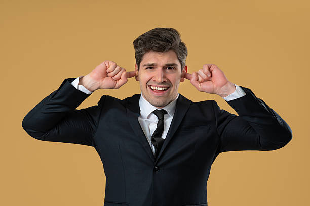 istock Businessman covering ears, showing irritation in beige studio. Stress, overload 2228833295