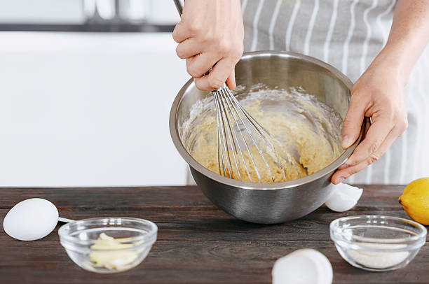 istock A cook in an apron kneads the dough in a bowl using a whisk for baking bread, dessert, pie, buns. Homemade or handmade bread, dessert. Kitchen background. 2228838320