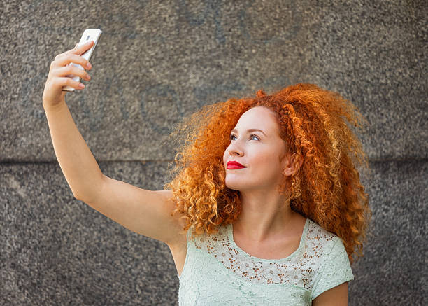 Happy young woman taking selfie while relaxing outdoors