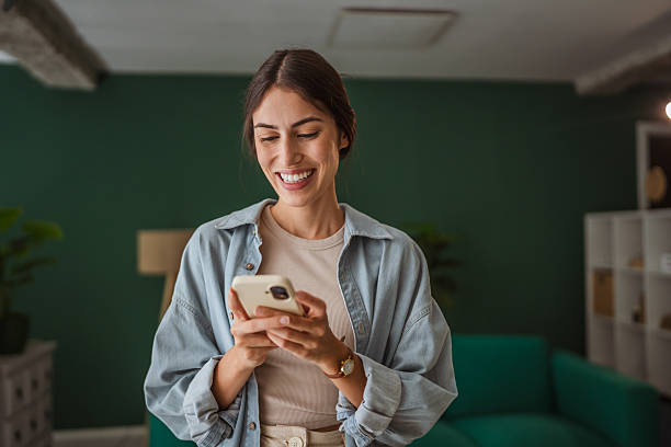 istock Happy woman using smart phone at home: smiling while reading good news 2228839980