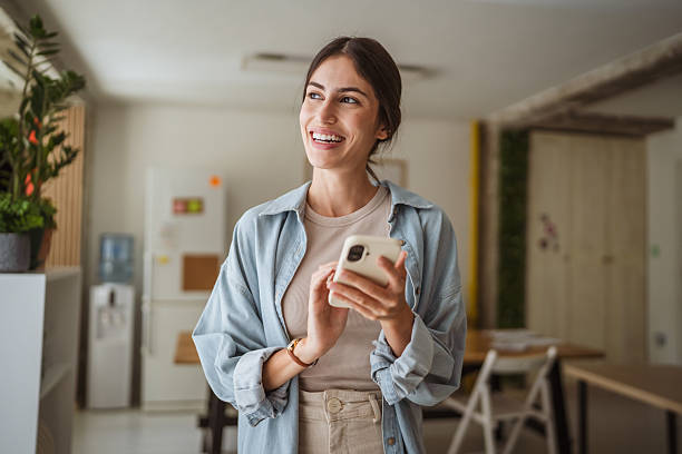 istock Happy businesswoman using mobile phone in office break room 2228840001