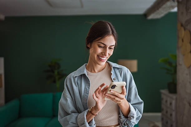 istock Happy woman using smart phone at home: smiling while reading good news 2228840003
