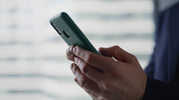 istock Businessman hands texting mobile phone in light office interior closeup. 2228842171