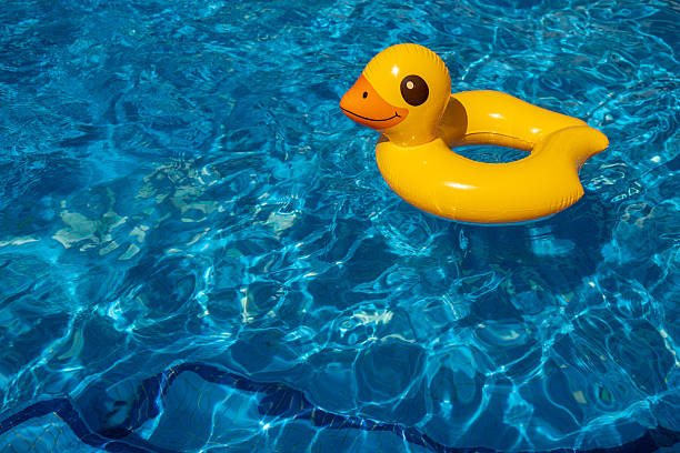 The girl pushes the yellow rubber duck toy underwater