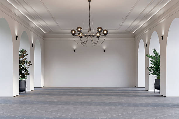 istock Modern empty interior with elegant arched openings, decorative ceiling molding, chandelier and decorative potted plants on light gray tiled floor 2228844915