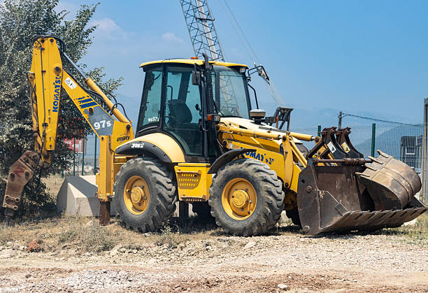 A yellow excavator stands at the site of planned repairs to underground communications, heating, and water supply systems.