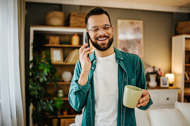 istock Young man talking on the phone and drinking coffee at home 2228847013