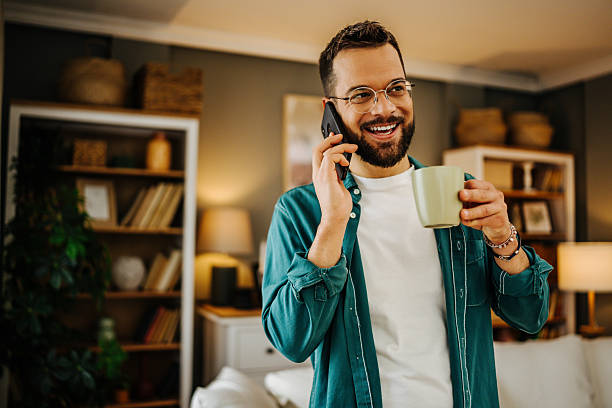 istock Young man talking on the phone and drinking coffee at home 2228847018