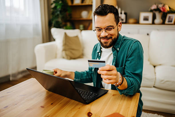 istock Young man making online payment using credit card and laptop at home 2228847051