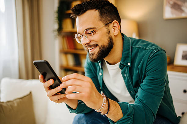istock Young man using smartphone and smiling at home 2228847110