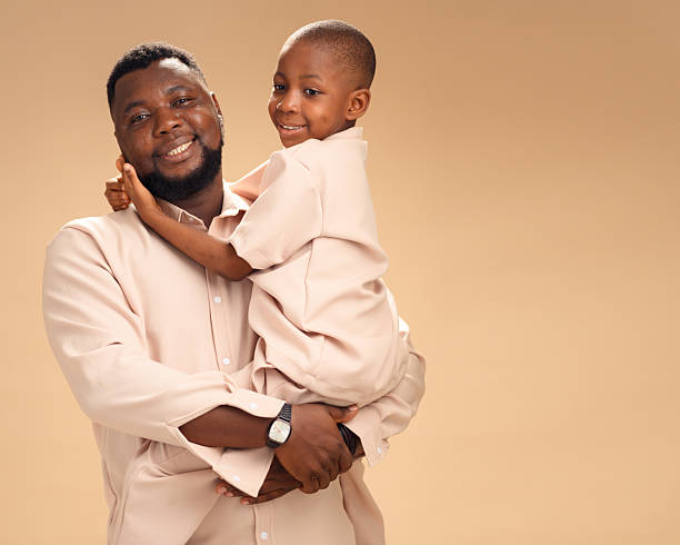 istock African father embracing smiling son in beige, studio portrait 2228849585