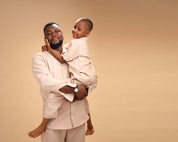 istock Father embraces son with joy in soft-lit studio portrait. 2228849626