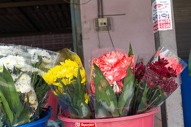 A woman florist hands a beautiful bouquet of flowers to a happy customer inside a cozy shop filled with vibrant plants and natural decor, capturing the atmosphere of gifting and personalized service.