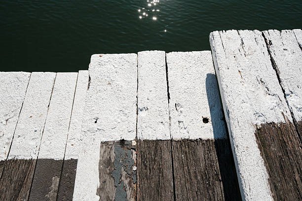 Close-up on an old outdoors wooden staircase bordered in white paint.