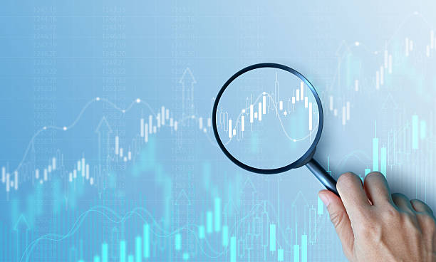 istock Hand holding magnifying glass analyzing digital financial stock chart. Data analysis, investment research, trading strategy, and financial market concept on blue background. business stock market. 2228869473