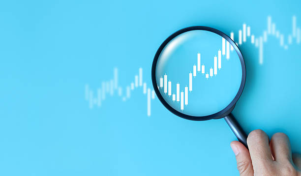 istock Hand holding magnifying glass analyzing digital financial stock chart. Data analysis, investment research, trading strategy, and financial market concept on blue background. business stock market. 2228869480
