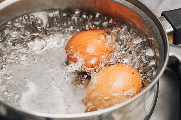 istock Boiling eggs in saucepan closeup. Two brown eggs cooking in hot bubbling water on kitchen stove. 2228873903