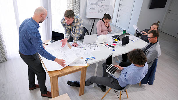 istock A group of people are sitting at a table in a conference room with laptops and documents. Discussion of the project drawings. A management company 2228876845