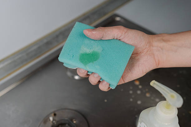 istock Professional housekeeper hands squeezing liquid cleaner from bottle onto sponge, preparing to clean dirty stovetop, emphasizing domestic chores and hygiene. 2228879953