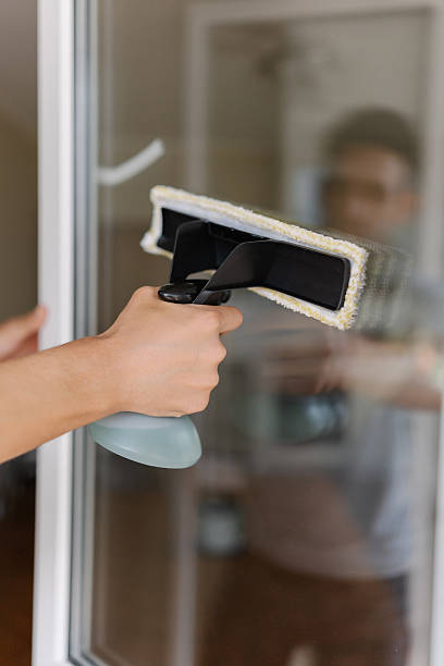 istock Professional cleaner male washing window using modern cleaning tool with integrated spray bottle and squeegee, ensuring spotless and streak-free finish. 2228880751