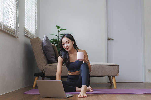 istock Young asian woman drinking tea and using laptop at home 2228880836