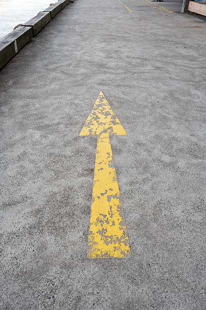 istock Old yellow arrow painted on a concrete floor 2228881868
