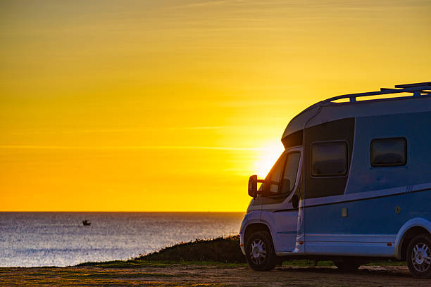 istock Camper car on beach at sunrise 2228883008