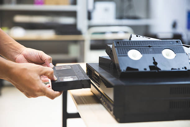 istock Close-up hand chooses and put or insert video cassette tape VHS on video record playback concept of retro style or vintage electric and electronic appliances multimedia player device old fashioned. 2228884133