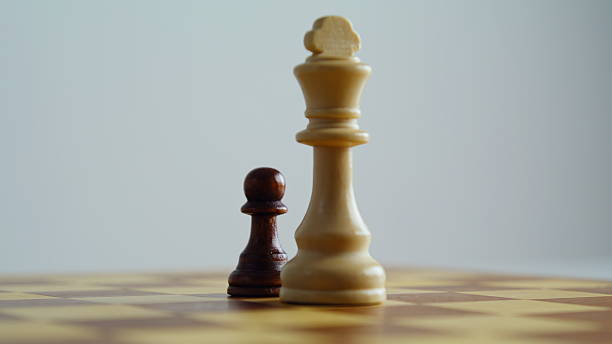 istock Closeup chess figures standing on chessboard. Brown pawn white king game pieces 2228889477