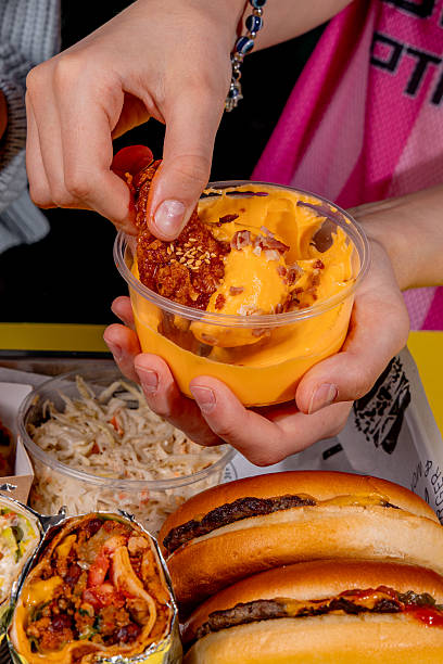 istock Girl dipping fried chicken wing into cheese sauce 2228890404