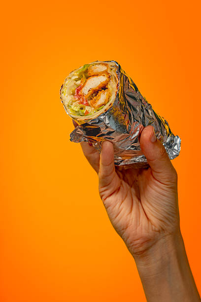 istock Hand holding bright juicy shawarma on orange background 2228890480