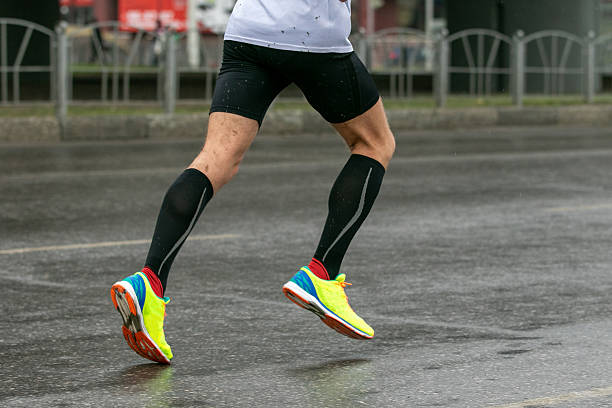 istock runner legs in compression socks and bright running shoes running on wet road 2228890664