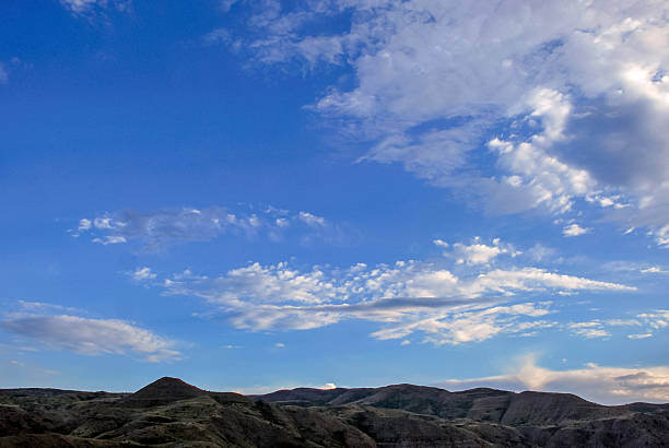 Rolling hills and expansive sky at sunset over serene landscape.