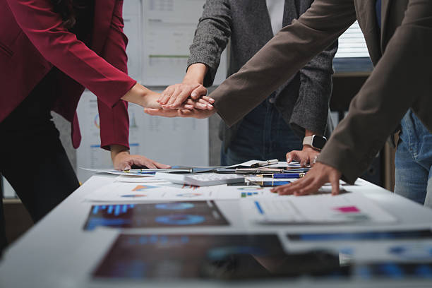 istock Business team joining hands over a table with charts and graphs 2228891686