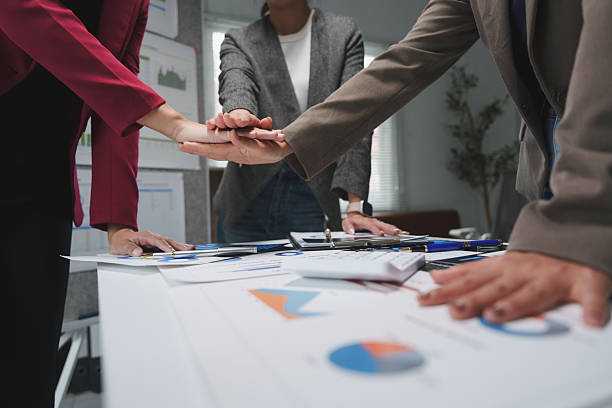istock Business team joining hands over table with charts and graphs 2228891690
