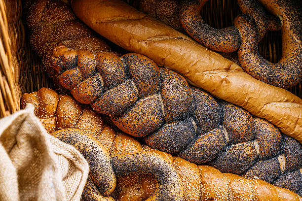 Assortment of Artisan Breads Including Twisted Loaves and Baguettes Arranged in Wicker Baskets at Outdoor Market Stall