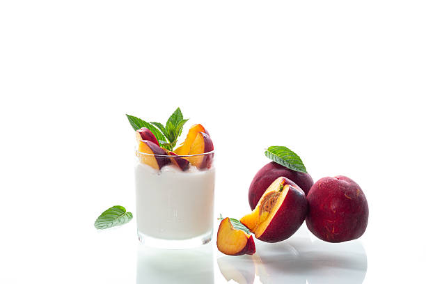 Whole and cut nectarines with yogurt on clean background