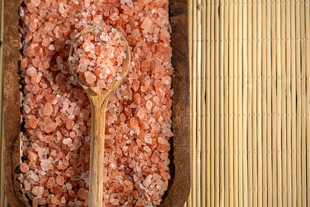 Aerial view of himalayan salt with wooden spoon. Close up studio shot. No visible human presence.