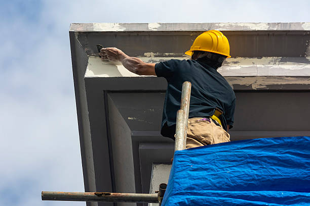 istock A skilled construction worker in a hard hat standing on top of scaffolding sanding the corner of the eaves and fascia of a 3 story house. Exterior renovation of a building facade. 2228892927