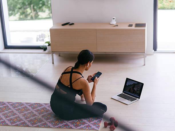 istock Woman Checking Phone While Watching Fitness Video 2228893937