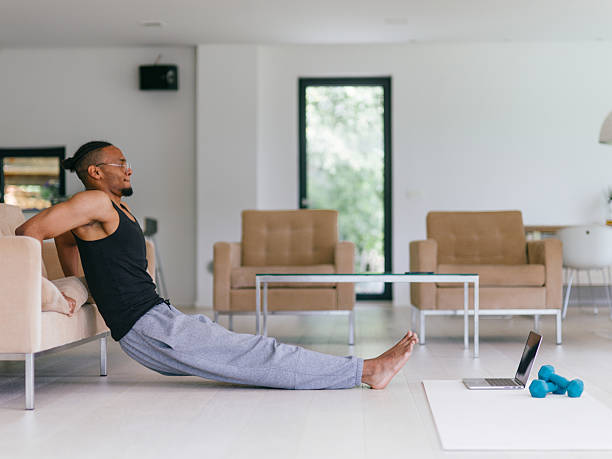 istock Training At Home. Sporty man doing the training while watching an online tutorial on a laptop, exercising in the living room, free space. 2228898089