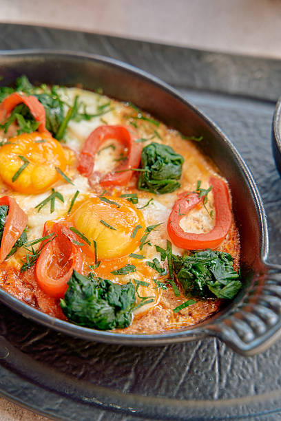istock Deliciously baked eggs with fresh spinach, vibrant tomatoes, and fragrant herbs in a sizzling dish, perfect for brunch or a hearty meal. 2228902590
