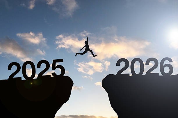 Silhouette Man jumping from 2025 cliff to 2026 cliff with cloud sky