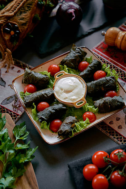 istock A Close-Up Look at a Traditional Dish Featuring Dolma Wrapped in Grape Leaves, Accompanied by Fresh Cherry Tomatoes and Creamy Dip on a Rustic Table Setting 2228907671