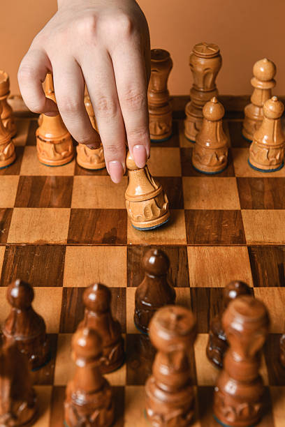 istock Female Hand Advancing Chess Piece Toward Opponent On Checkered Board 2228910837