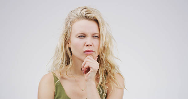 Confused, uncertain and woman with thinking in studio for decision, planning and solution to doubt. Mockup space, person and suspicious on white background for fake news gossip, contemplating or liar