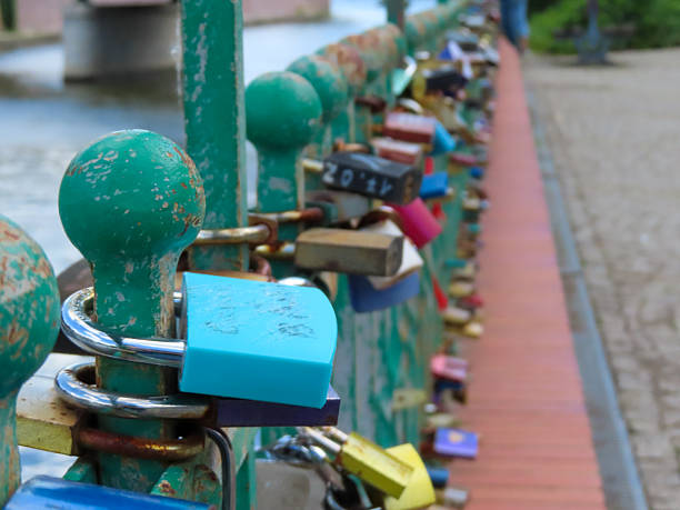 Colorful padlocks attached to a green iron fence on a bridge, symbolizing love and commitment in an urban romantic tradition.
