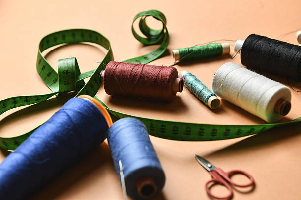 Close-Up Of Colorful Thread Spools With Sewing Items Against Brown Background