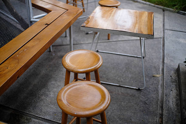 istock Rustic wooden tables and stools arranged outdoors on a concrete surface create a minimalist ambiance with natural tones and shadows casting on the scene highlighting the simple wood material 2228921352