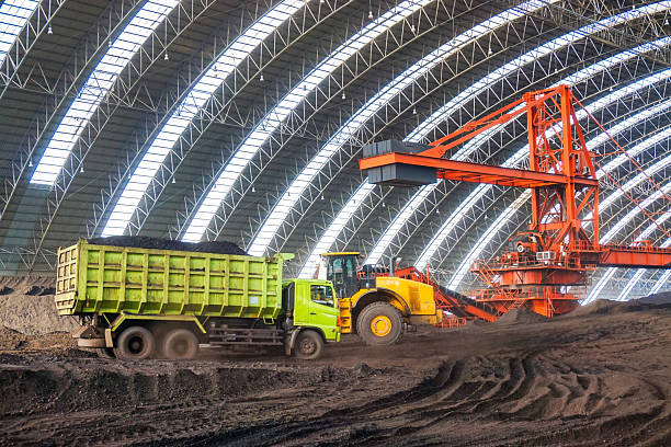 istock Industrial coal handling operations featuring a stacker reclaimer and haul truck under a structured arched roof for materials processing 2228921491